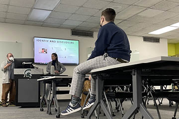 Student sits upon a desk while listening to presentation