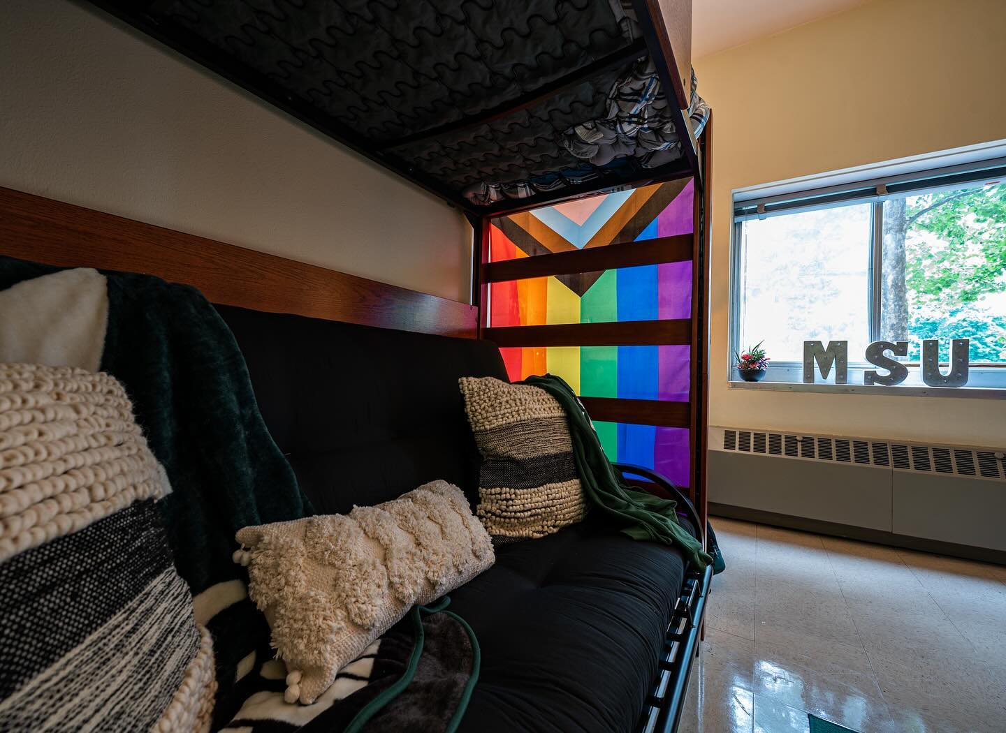 A progress pride flag hangs in a residence hall room.