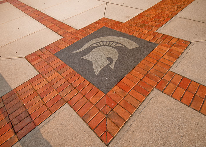 The Spartan helmet is pictured in cement on the ground on MSU's campus.