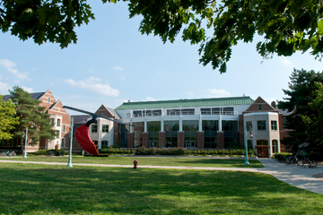 The Gallery at Michigan State University on a clear day, featuring a lawn and a red sculpture in front of the building. The hall is part of the university's residential campus.