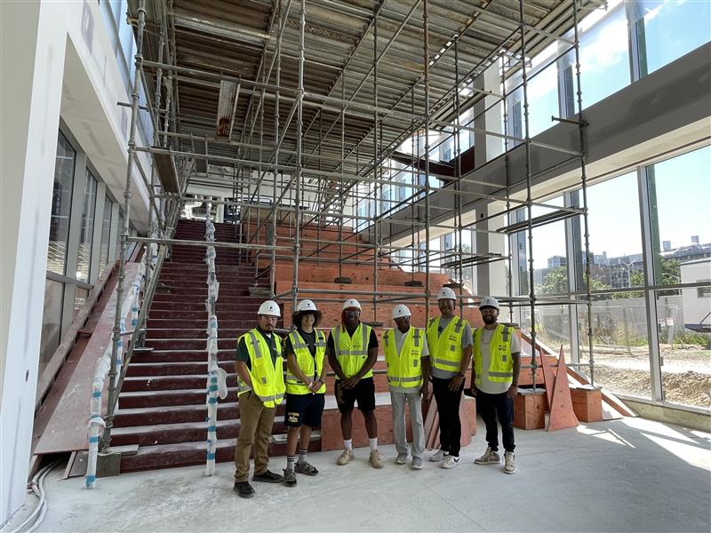 Members of the Office of Multicultural Enrichment and Advocacy stand at the base of the stairway in the still-under-construction Multicultural Center.