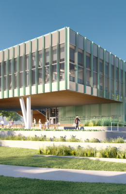 Daytime view of Michigan State University's Multicultural Center. The modern building features large glass windows and a cantilevered design, supported by white structural beams. The surrounding landscape includes lush greenery and a pathway, with individuals walking and enjoying the inviting space.