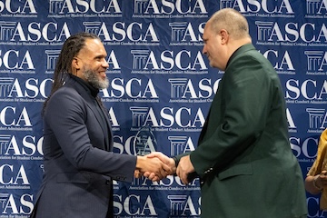 Dr. Kyle Williams shakes Rick Shafer's hand as Rick accepts his award.
