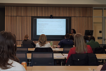 Attendees watch a presentation on the challenges student caregivers encounter.