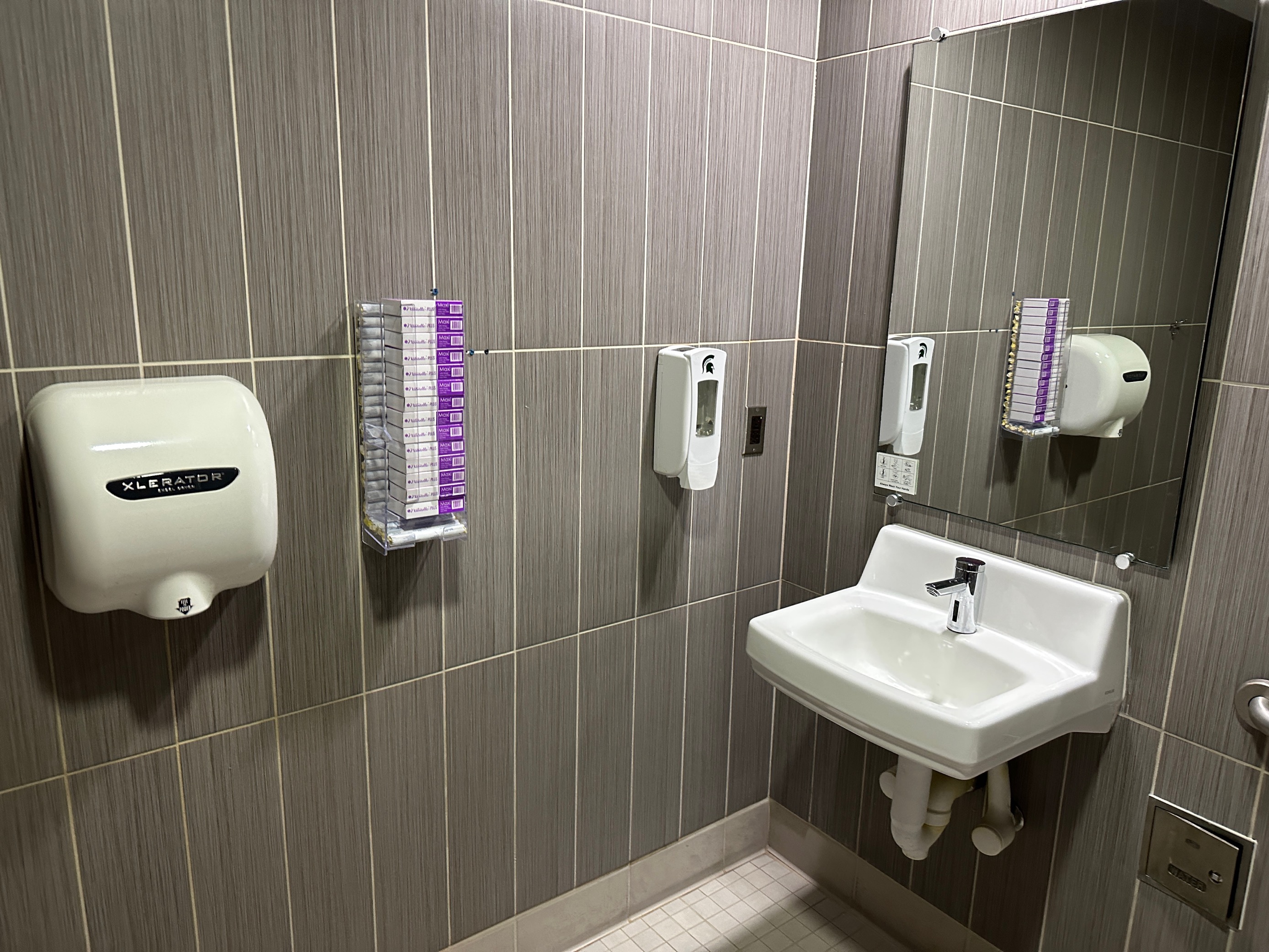 Bathroom with menstruation dispenser hanging on wall